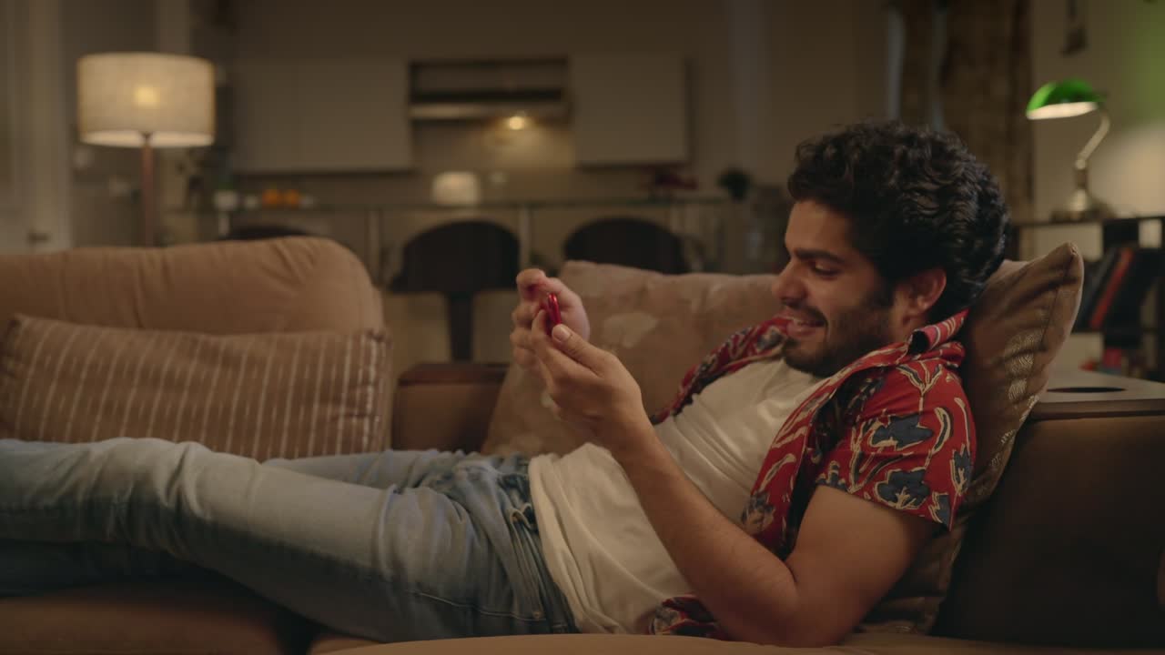 joven indio descansando en un sofá viendo una plataforma en línea en casa