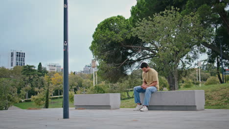 student watching funny video on cellphone sitting city bench. happy man laughing