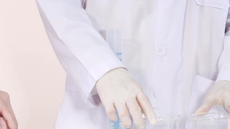 a scientist in a white coat carefully handles chemicals using glassware and a dropper in a laboratory setting.