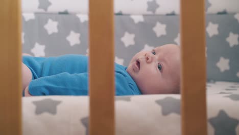 funny newborn baby in bodysuit rests in cozy crib at home