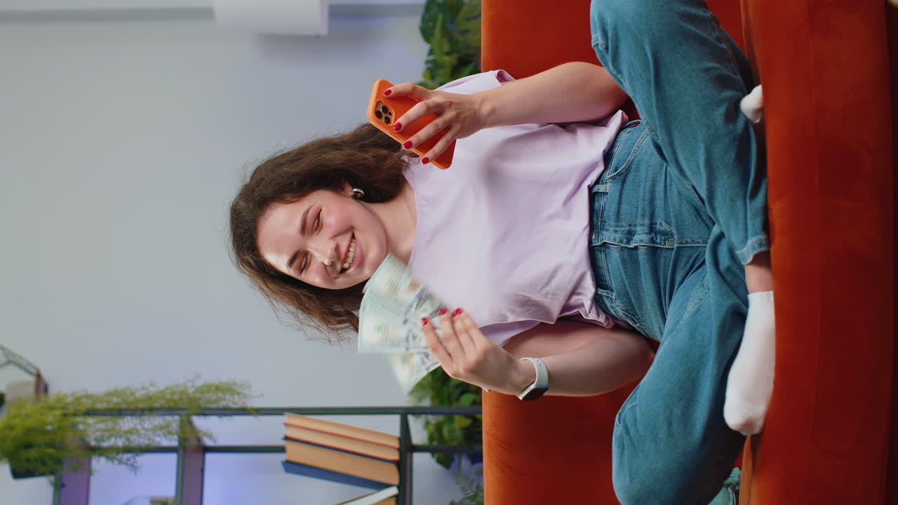 mujer joven sonriente feliz contando dinero en efectivo uso de teléfono inteligente ingresos ahorra lotería ganar presupuesto en casa