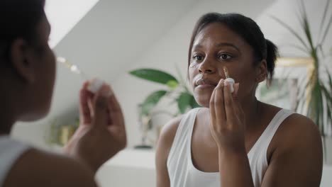 Afroamerikanische-Frau,-Die-Im-Badezimmer-Serum-Zum-Gesicht-Verwendet.