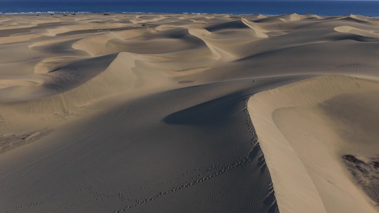Splendide riprese aeree che mostrano le dune di sabbia ondulate della Riserva Naturale delle Dune di Maspalomas a Gran Canaria, Isole Canarie, Spagna.