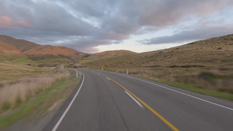 driving through the motorway along the hills and countryside fields in south otago, new zealand