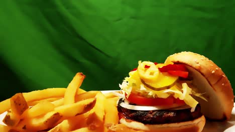 hamburguesas y papas fritas sin piel en un plato con un fondo verde cromado como un plato blanco que gira 360 grados en una combinación jugosa de carne con marcas de parrilla en pan kaiser con sésamo y guarniciones 1-2