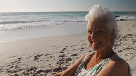 Senior-woman-sitting-looking-away-at-the-beach