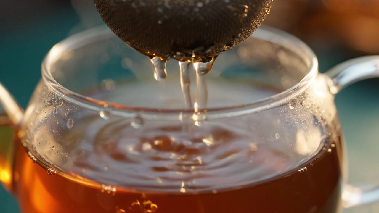 Preparare una tazza di tè perfetta: un primo piano di un infusore che infonde foglie di tè in una teiera trasparente con vapore che sale, catturando l'essenza del comfort.