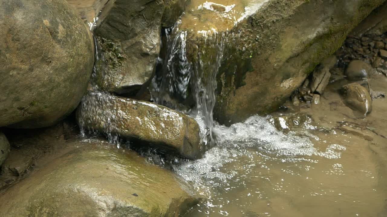 Slow Motion of Water Stream Flowing over Timeworn Rocks in the Heart of a Forest