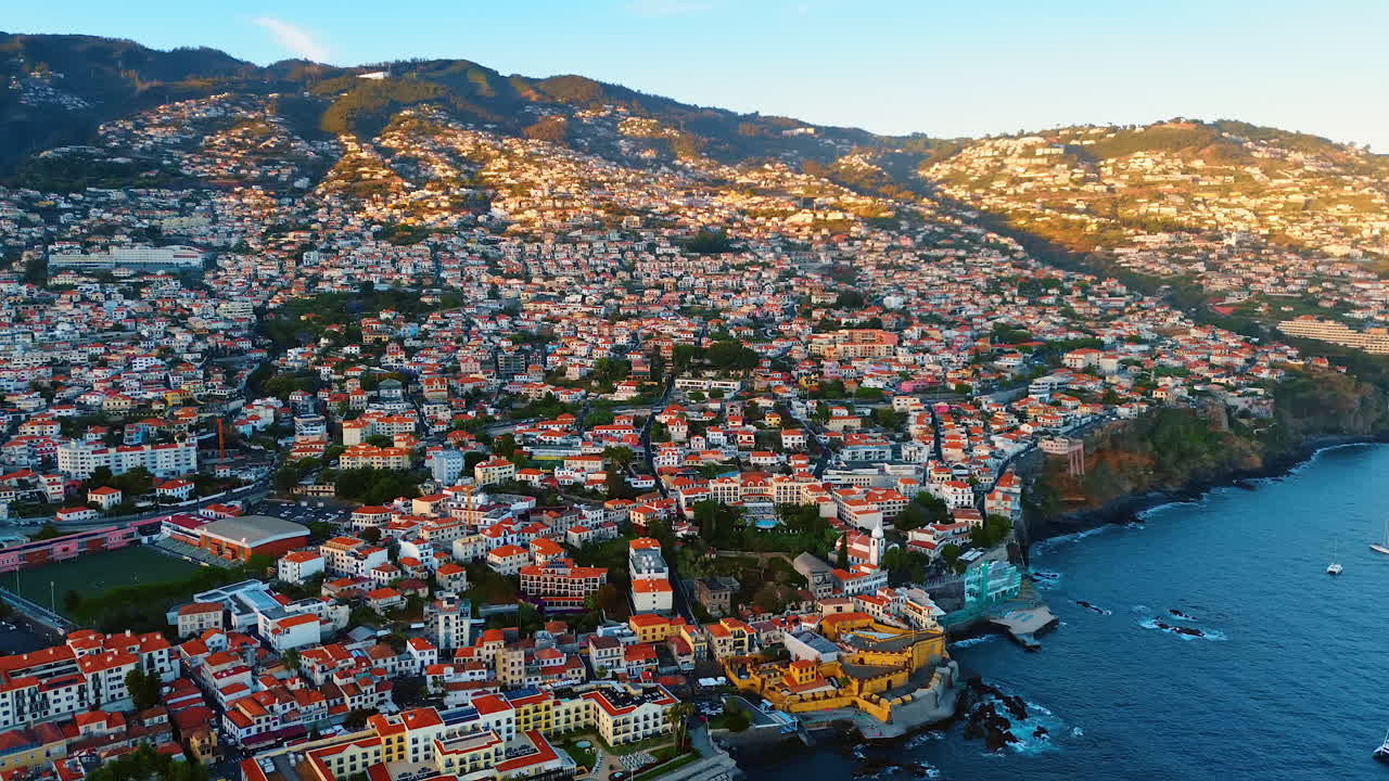 Highly populated mountain slope at the Atlantic Ocean shore. Scenery of the picturesque town at the Madeira Islands, Portugal. Top view.