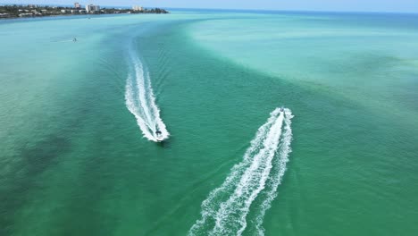 camera is flying between boats as they cross paths near the opening of a small bay into the wide ocean