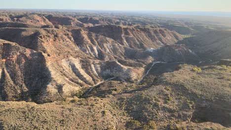 High-drone-view-over-a-streched-hilly-red-charles-Knife-Canyon-on-a-foggy-day-during-sunrise-In-Exmouth,-Western-Australia