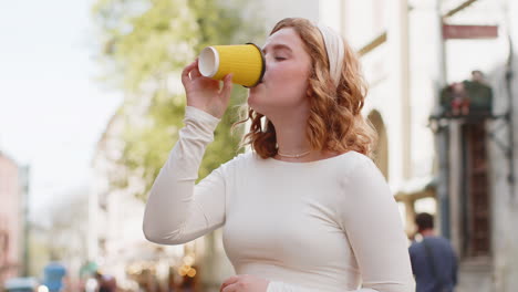 happy young woman enjoying drinking morning coffee hot drink relaxing taking a break in city street