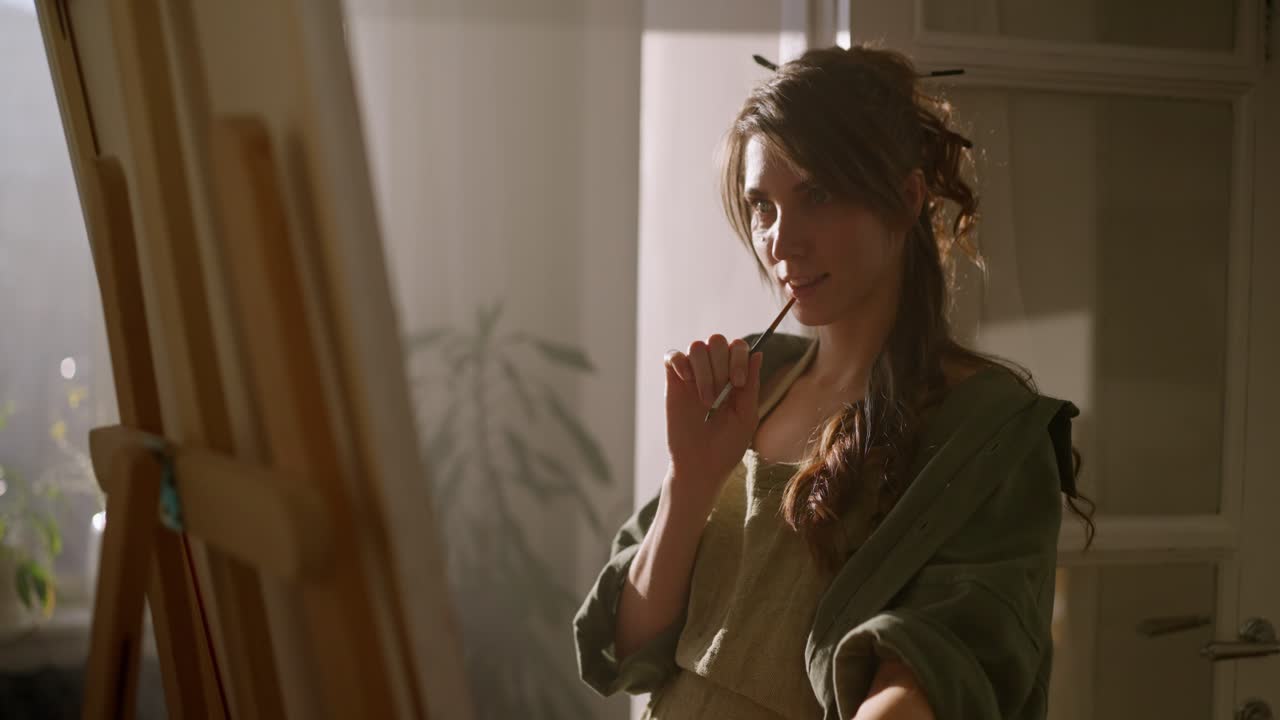 mujer pintando en un caballete en un estudio soleado