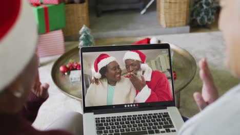 Diverse-senior-female-friends-using-laptop-for-christmas-video-call-with-happy-couple-on-screen