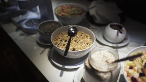 delicious slow closeup detailed shot of food bowls at hotel breakfast, including oatmeal, sweet cereals, porridge, fruits and others