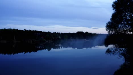 mysterious evening during blue hour on the lake with fog