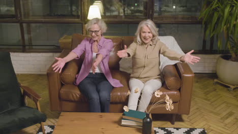 two little girls running and hugging their happy grandmothers who sitting on sofa in the living room at home 2