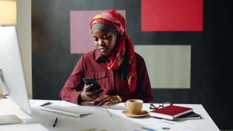 Mujer-Negra-Usando-Un-Teléfono-Inteligente-En-El-Escritorio