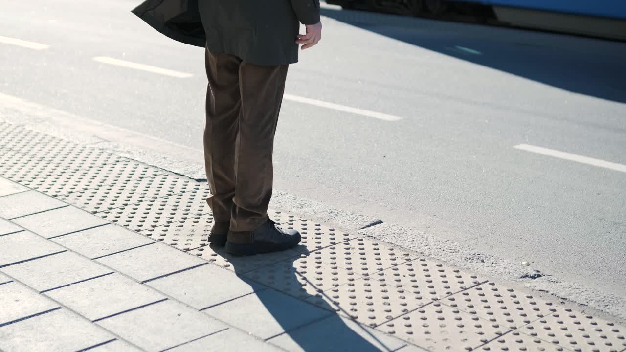 Visually impaired man crossing the road with his stick with the help of tactile pedestrian sidewalk for the visually impaired in the city.