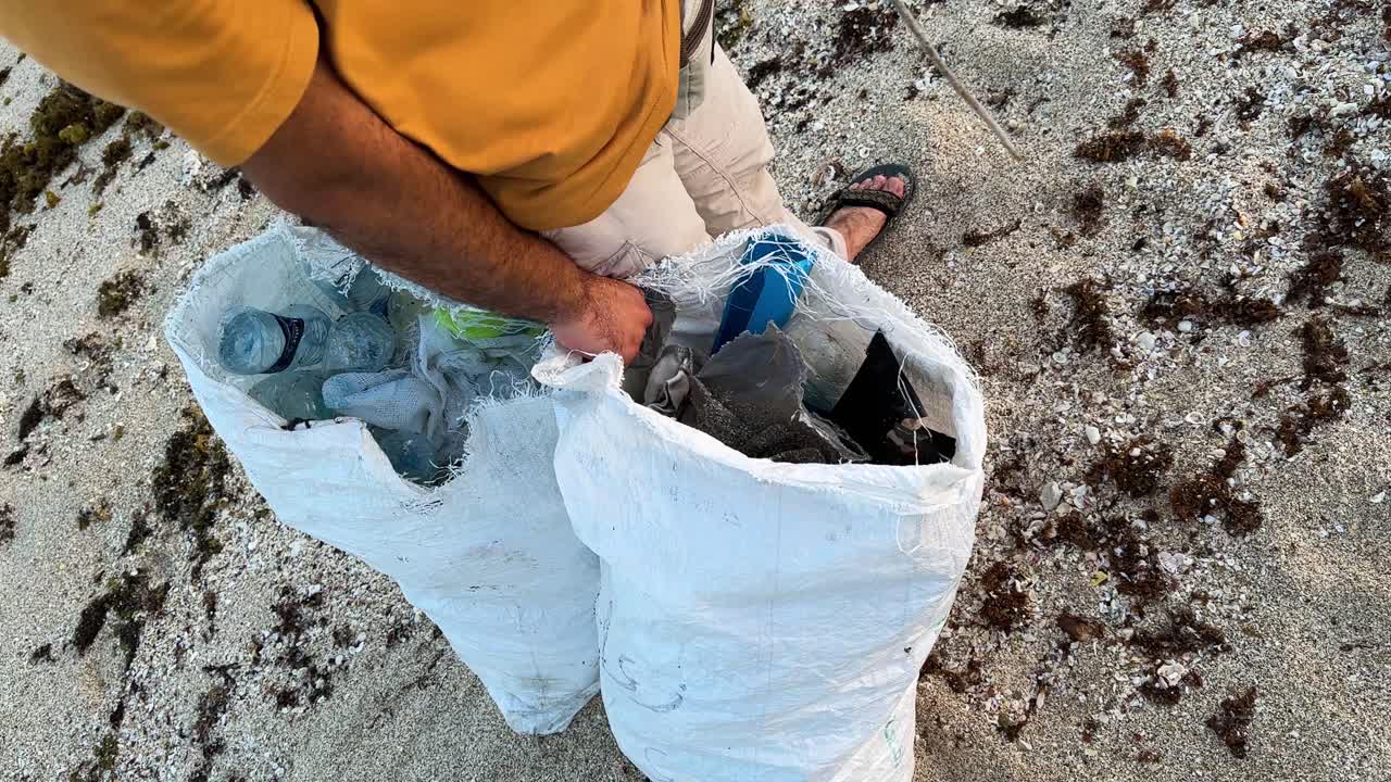 beach conservation activity tackling ocean pollution in Iran tropical seaside plastic bottles trash bags being collected to protect environment rural village efforts for clean beautiful sandy beaches