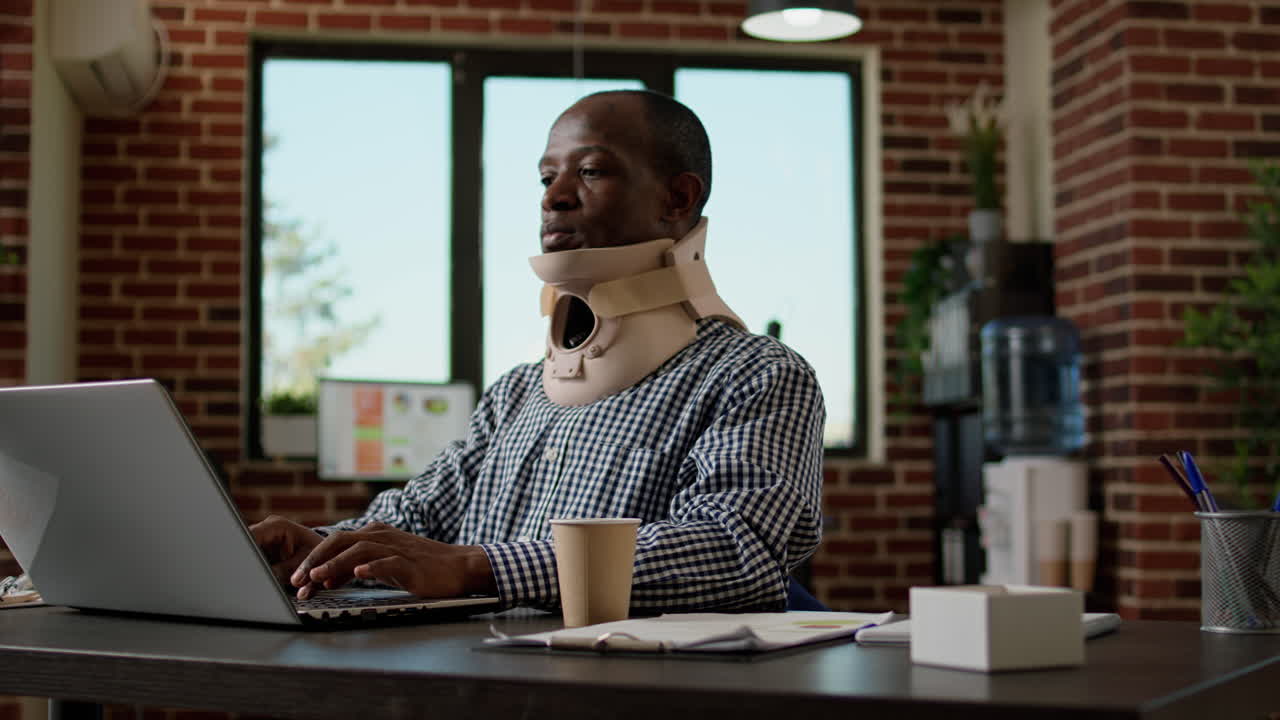 Office worker in pain working with medical neck foam at desk