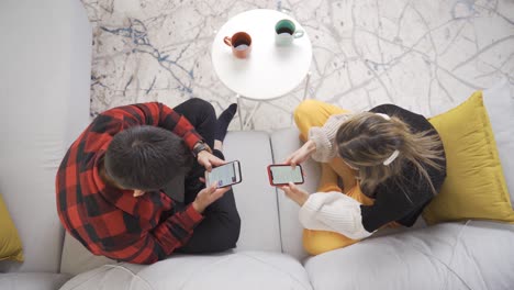 young couple using two smartphones are phone addicts.