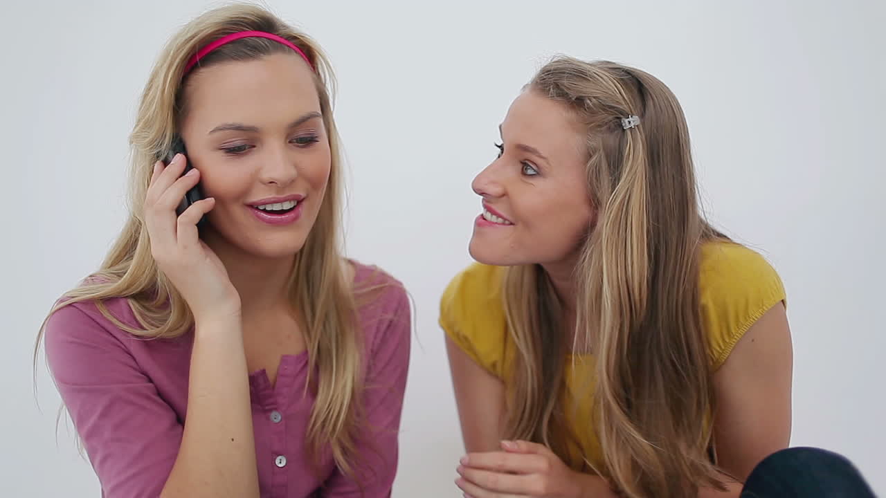 Woman whispering to her friends whos using a phone 