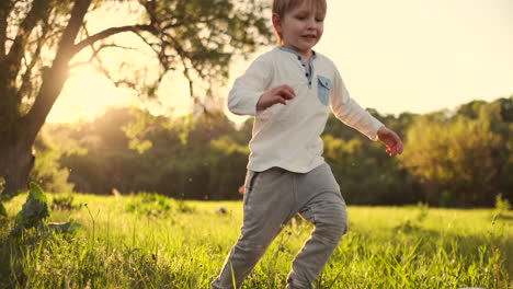 In-slow-motion-a-happy-boy-with-a-soccer-ball-runs-into-the-field-at-sunset-dreaming-of-playing-professional-football.