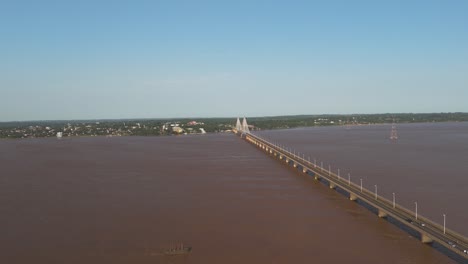 Aerial-forward-flight-over-Rio-Paraná-River-with-San-Roque-González-de-Santa-Cruz-Bridge-during-sunny-day