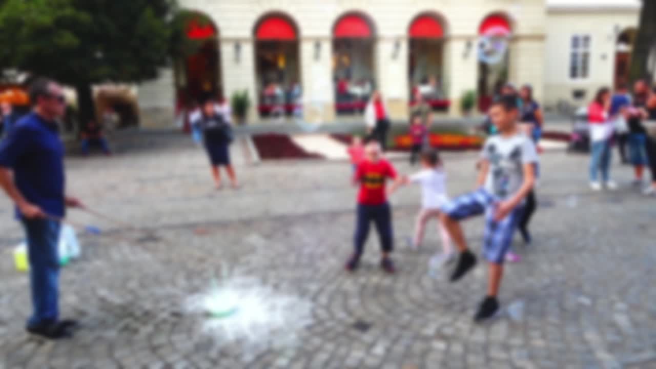 O homem entretém crianças com bolhas de sabão na praça da cidade. Fora de foco.