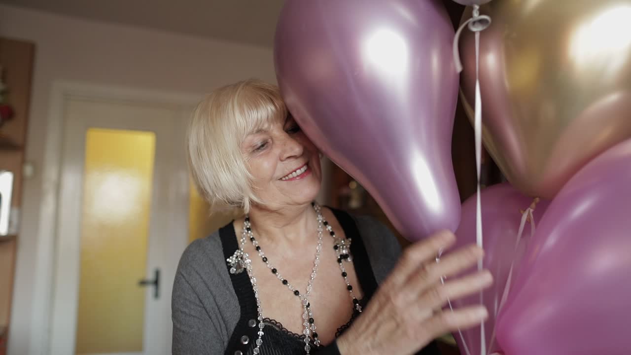 Una nonna adorabile festeggia il suo compleanno. Tiene palloncini multicolori tra le mani