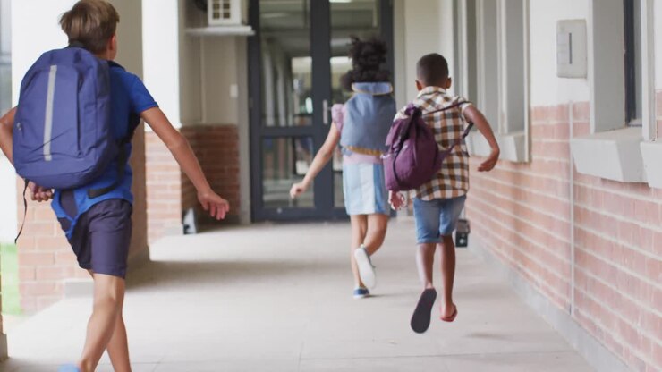 Video of back of diverse pupils running on school corridor