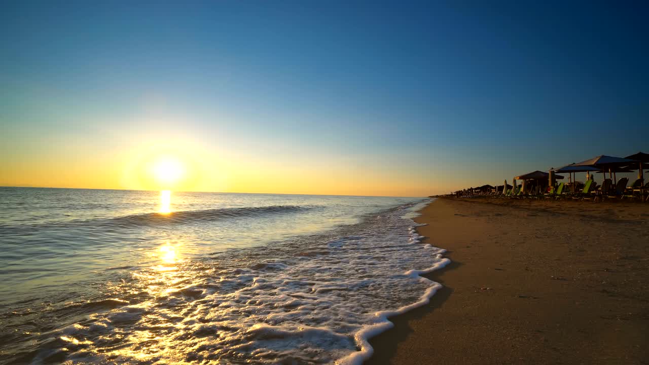 Ondas de surf espirrando na praia de verão ao pôr do sol, nascer do sol, fundo em loop