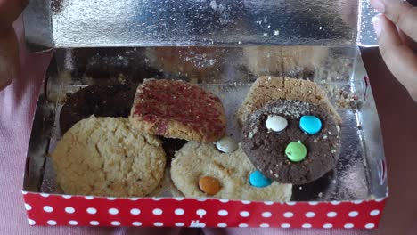 person eating assorted cookies from a box