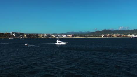 aerial view rising over a yacht in front of the coast of cabo san lucas, mexico