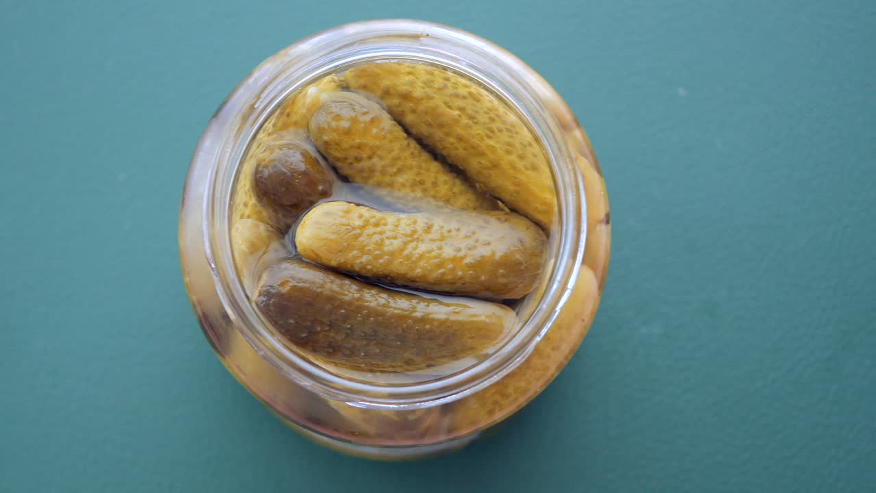 Jar of Pickles (Pickled Cucumbers) on a Green Background