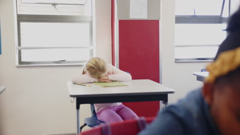in school, girl resting head on desk in classroom, looking tired