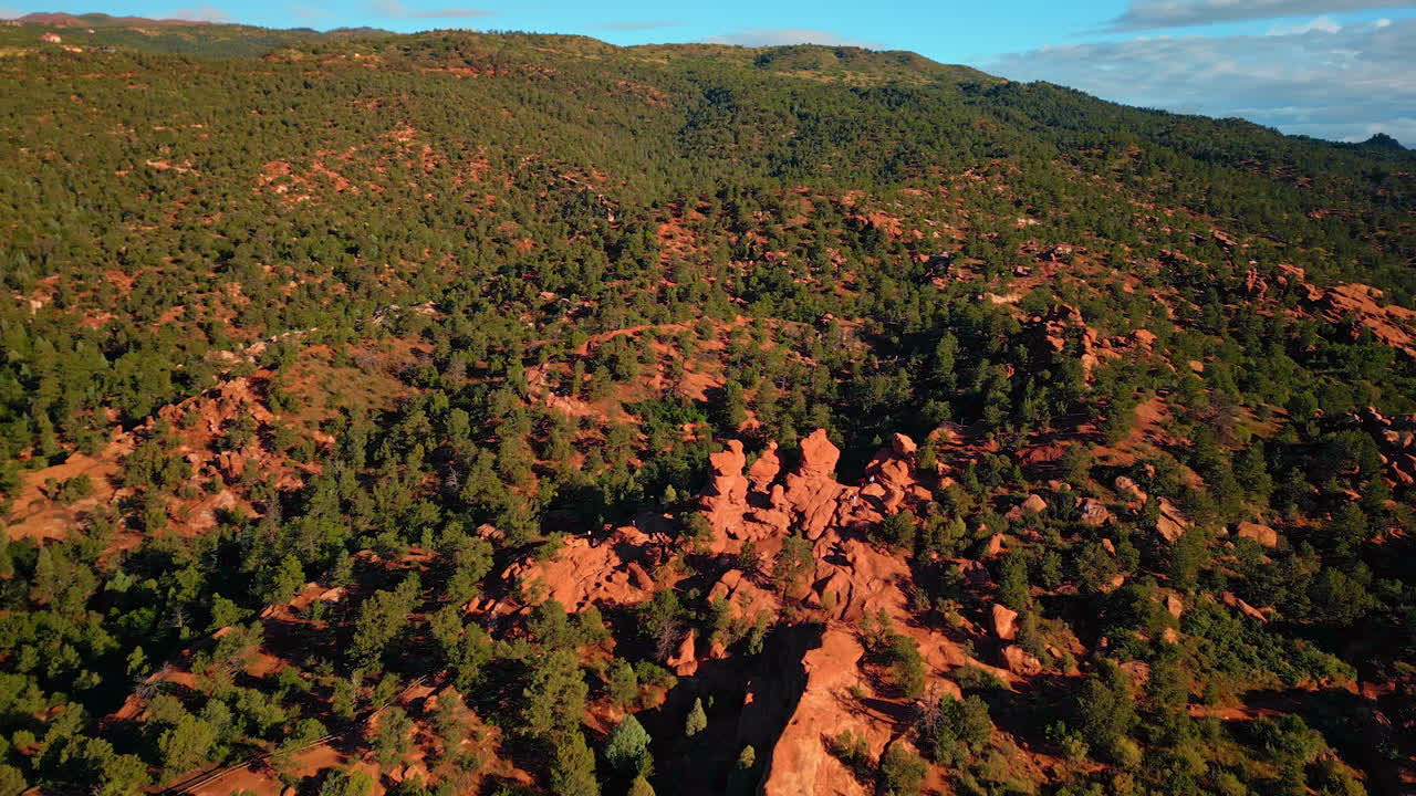 Bright sun lights the red clay rocks covered with greenery. Drone flight above the scenery in Capitol Reef National Park, Utah, United States