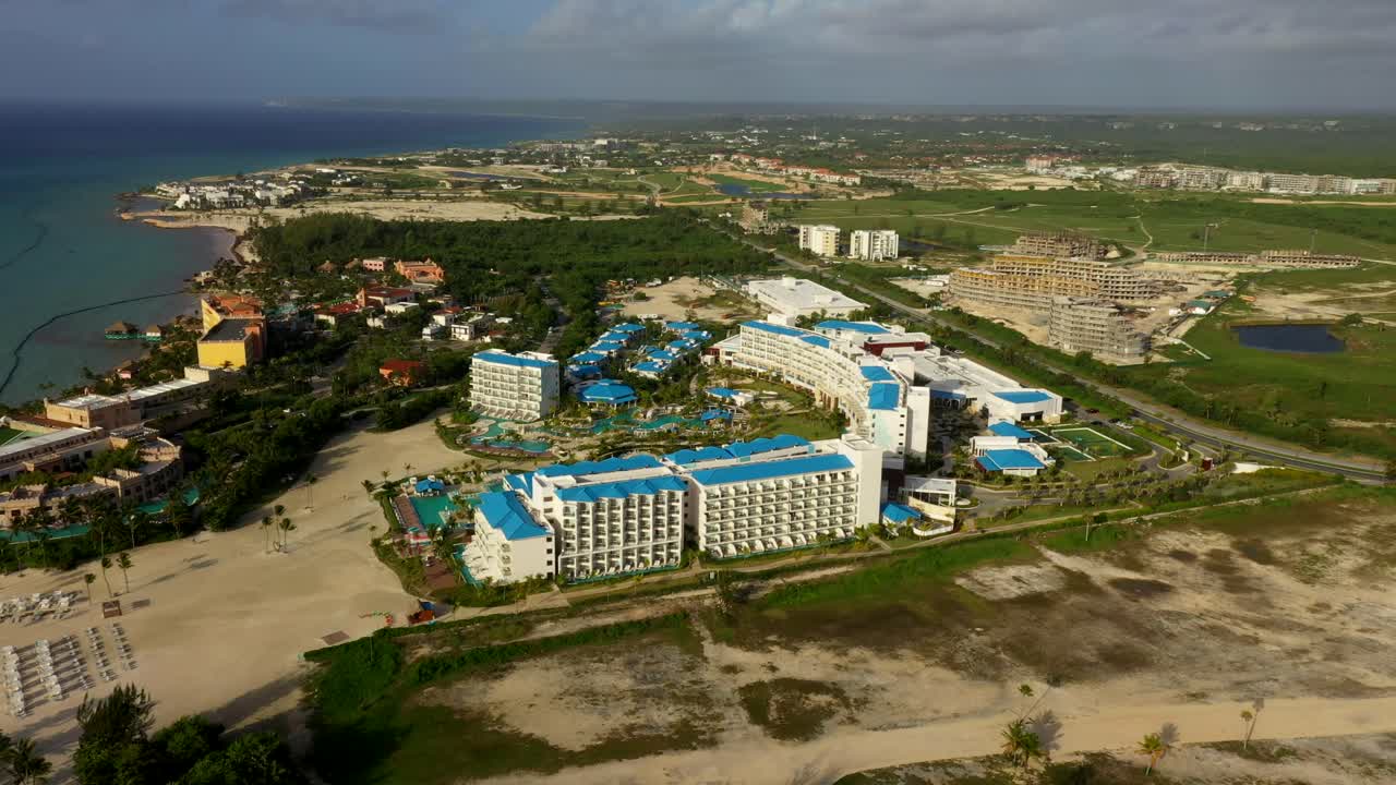 Drone che effettua un'orbita panoramica di piscina ed edifici del resort circondati dal verde a Cap Cana, Repubblica Dominicana