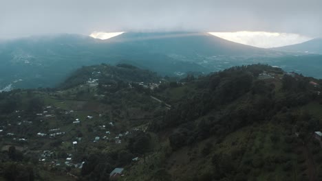 antena de drones volando sobre un hermoso valle verde durante una puesta de sol nublada, rayos de dios, paisaje volcánico en guatemala
