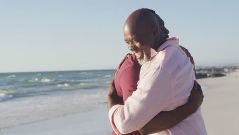 Video-Eines-älteren-Afroamerikanischen-Vaters-Und-Eines-Erwachsenen-Sohnes,-Die-Sich-Am-Strand-Umarmen