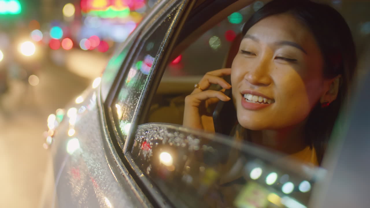 Asian Woman Talking on Phone while Riding in Car at Night