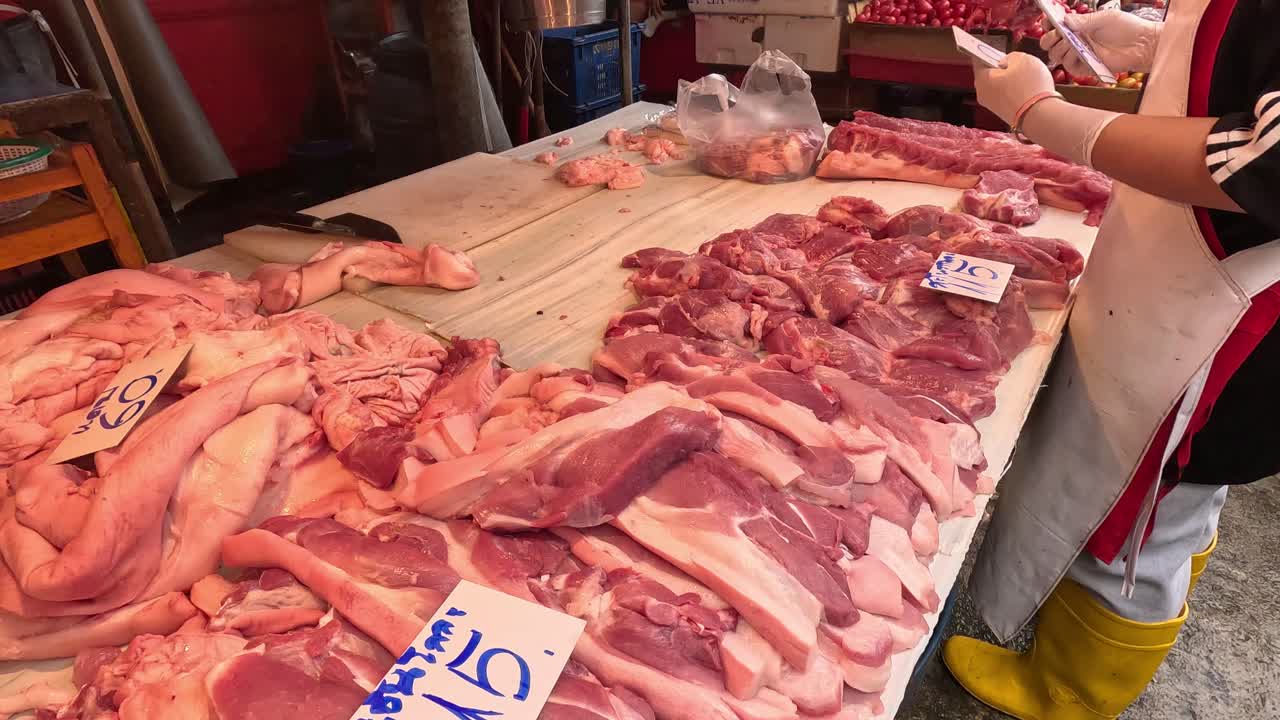 Person organizing fresh meat on a market stall