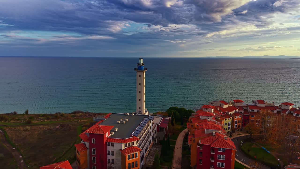 Un faro luminoso si erge imponente accanto al sereno oceano sotto un cielo spettacolare al tramonto, evocando un senso di calma e avventura.