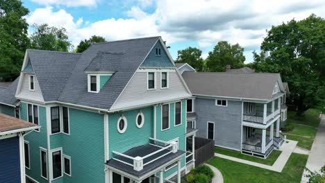 a view of residential houses with detailed architecture, featuring gabled roofs, balconies, and pastel sidings