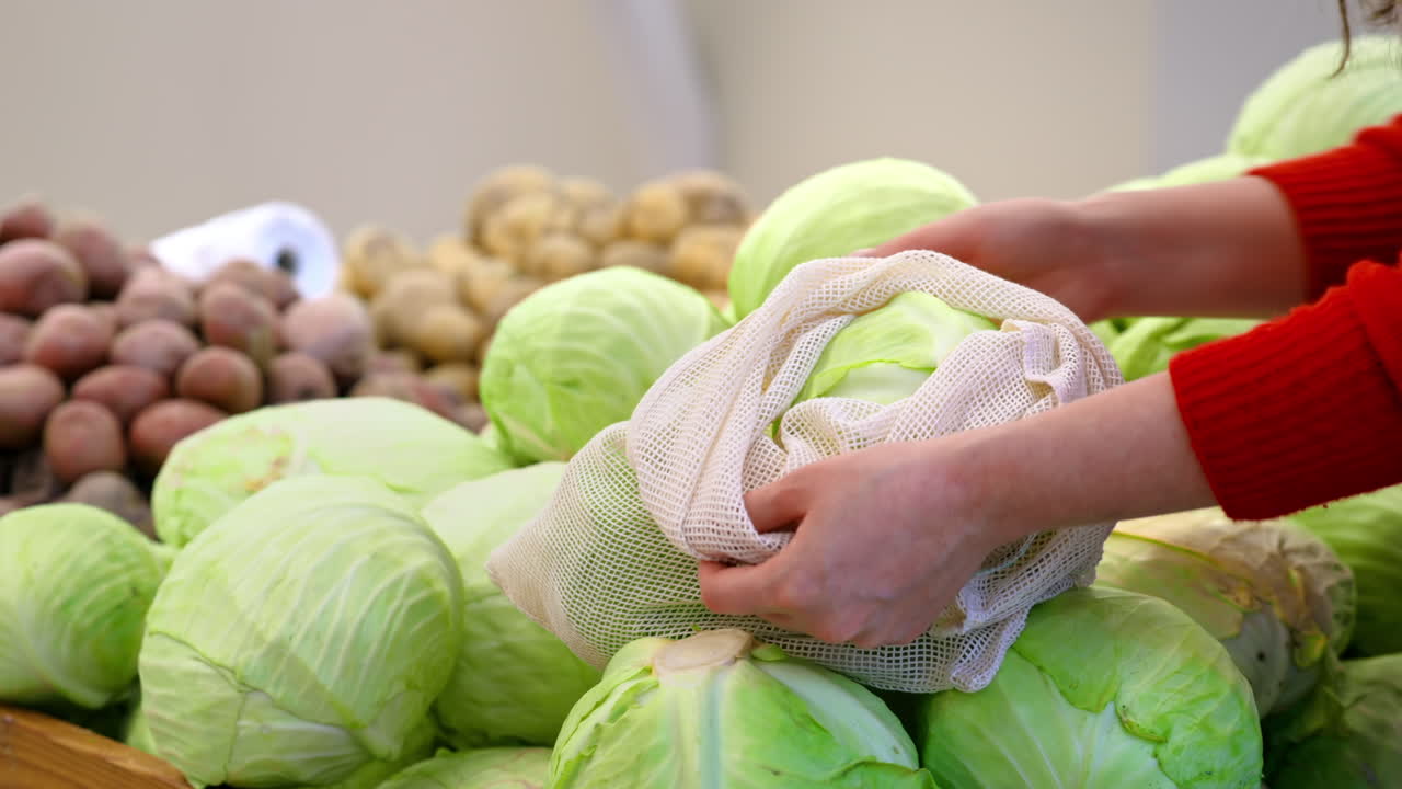 Woman picking white cabbage in a reusable bag in a store. Ecology and Earth Day thematics