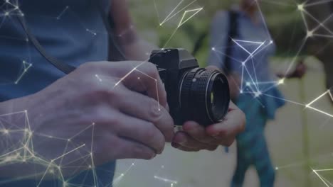 Network-of-connections-over-hands-of-caucasian-senior-man-using-digital-camera-in-countryside