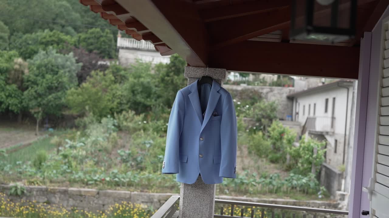 Elegant light blue suit jacket neatly displayed on a hanger outdoors on a porch