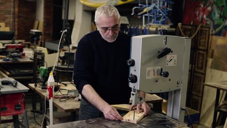 portrait of an adultgrey haired man working with milling machine while carving a wooden pattern in a working room at workshop . action. woodworking industry