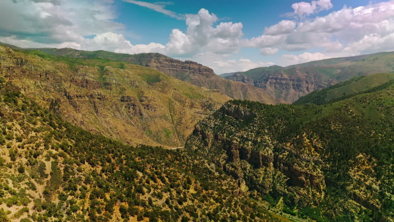 Flying above the mountains overgrown with pine trees and bushes. Two highways winding among the mountains in Colorado.